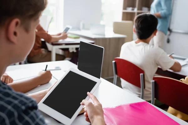 Verschwommener Junge zeigt auf digitales Tablet mit leerem Bildschirm im Klassenzimmer — Stockfoto