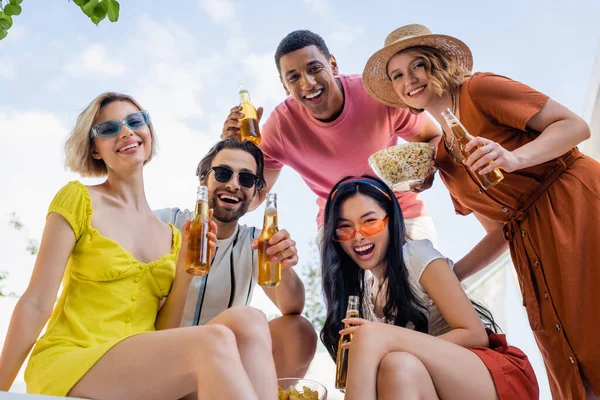 Tiefblick auf multiethnische Freunde mit Bier und Snacks, die im Freien in die Kamera lächeln — Stockfoto