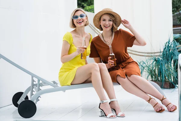 Femme élégante avec des bouteilles de bière souriant à la caméra pendant la fête dans le patio — Photo de stock