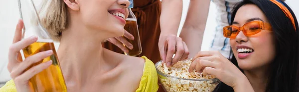 Счастливые многонациональные друзья едят попкорн во время пивной вечеринки, баннер — стоковое фото