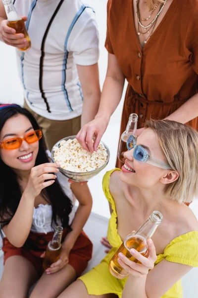 Amigos multiculturais alegres bebendo cerveja e comendo pipocas durante a festa de verão — Fotografia de Stock