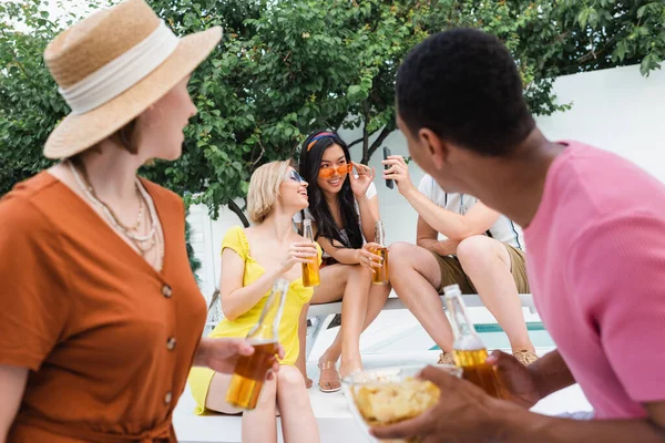 Flou afro-américain homme et femme en chapeau de paille près d'amis multiethniques ayant fête d'été — Photo de stock