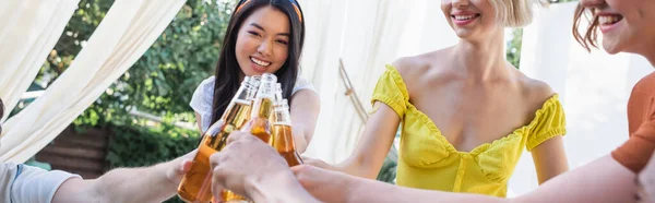 Smiling asian woman toasting with beer near friends outdoors, banner — Stock Photo