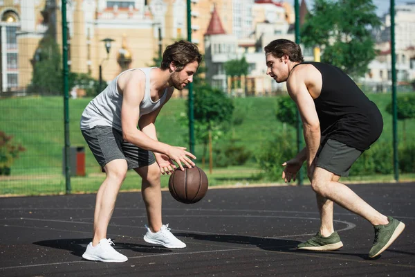 Vista laterale di giovani uomini che giocano a basket all'aperto — Foto stock