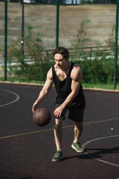 Esportista muscular jogando basquete na quadra ao ar livre — Fotografia de Stock