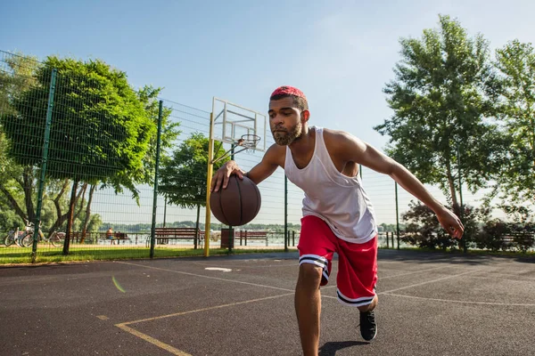 Африканский американский спортсмен играет в баскетбол на открытой площадке — стоковое фото