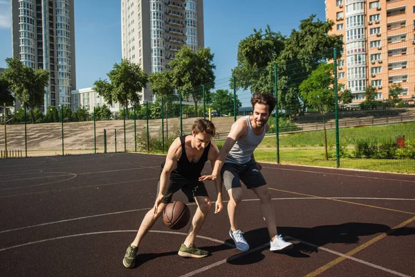 Les jeunes hommes s'entraînent tout en jouant au basket sur le terrain de jeu — Photo de stock