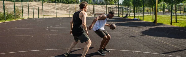Vista lateral do homem americano africano jogando basquete com amigo no playground ao ar livre, banner — Fotografia de Stock