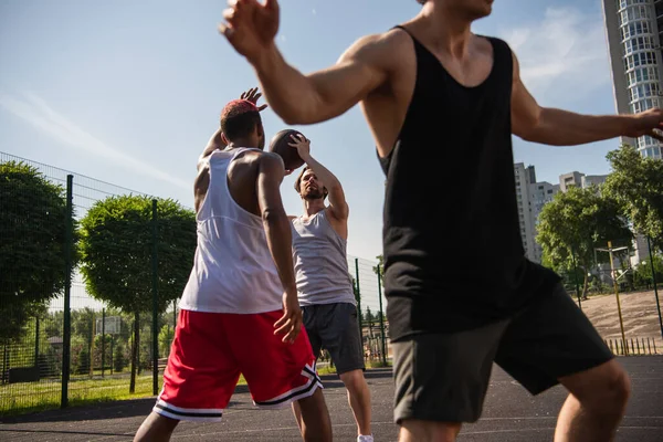 Deportistas multiétnicos jugando baloncesto en un parque infantil — Stock Photo