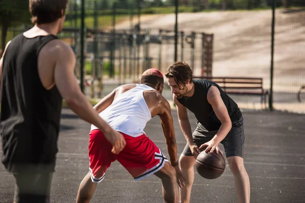 Desportistas multiétnicos jogando basquete no playground — Stock Photo