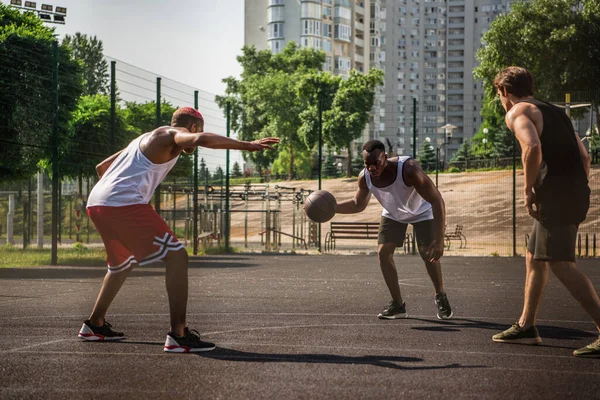 African american man playing basketball near friend on court — Stock Photo