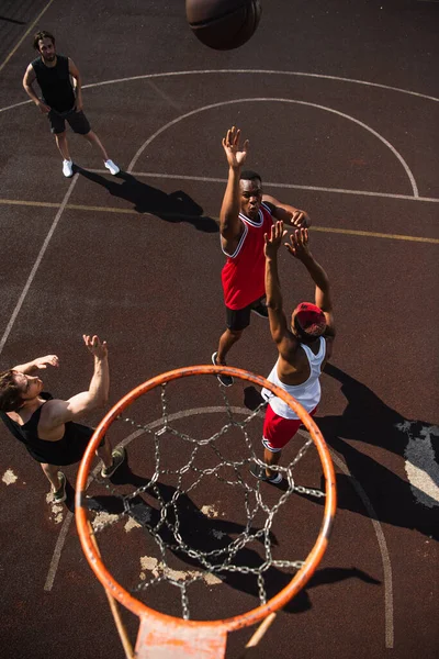 Overhead-Ansicht von interrassischen Männern, die Basketball in der Nähe von Reifen spielen — Stockfoto