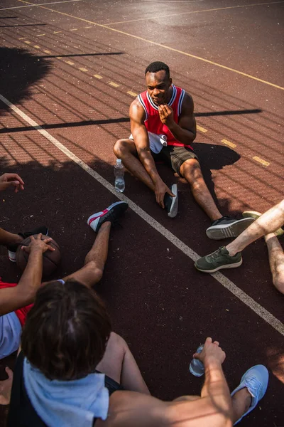 Visão aérea do esportista afro-americano conversando com amigos com bola de basquete no playground — Fotografia de Stock