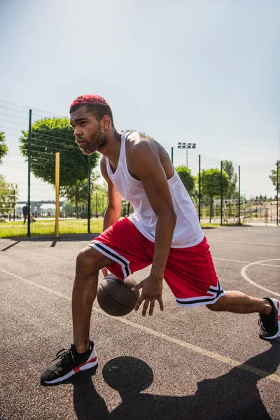 Desportista afro-americano jogando basquete no playground durante o dia — Fotografia de Stock