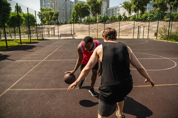 Multiethnische Männer spielen tagsüber Basketball auf Spielplatz im Freien — Stockfoto