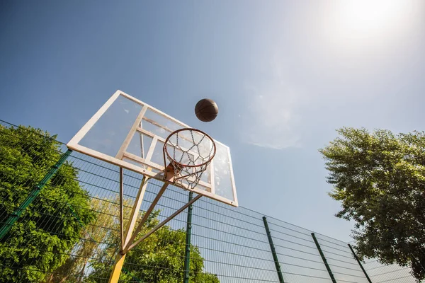 Low angle view of basketball ball near hoop on playground outdoors — Stock Photo