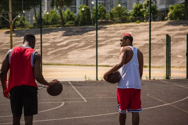 Des sportifs afro-américains avec des balles de basket sur une aire de jeux extérieure — Photo de stock