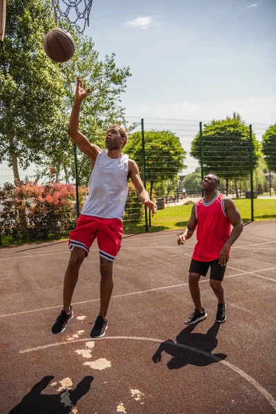 Basketteur afro-américain sautant près du cerceau et des amis — Photo de stock