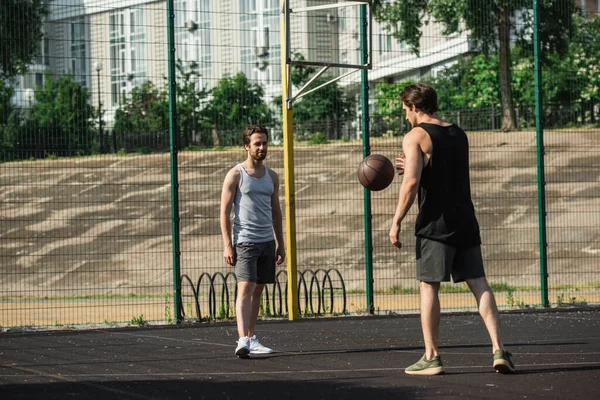 Мужчины в спортивной форме играют в баскетбол на площадке — стоковое фото