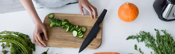 Visão parcial da mulher perto de pepino fatiado em cortar javali e abóbora madura na mesa, banner — Fotografia de Stock