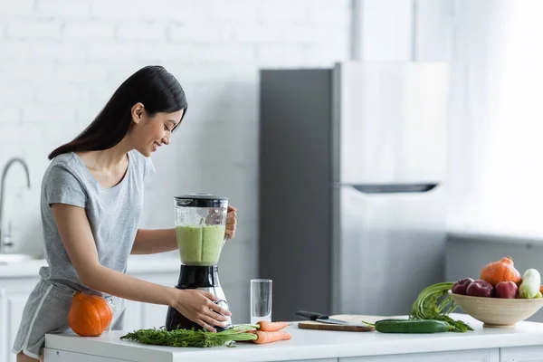 Happy asian woman preparing fresh smoothie for breakfast in kitchen — Stock Photo