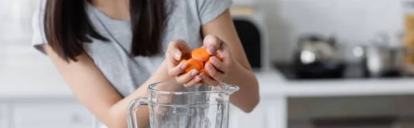 Vue partielle de la femme ajoutant la carotte tranchée dans le pot de shaker, bannière — Photo de stock