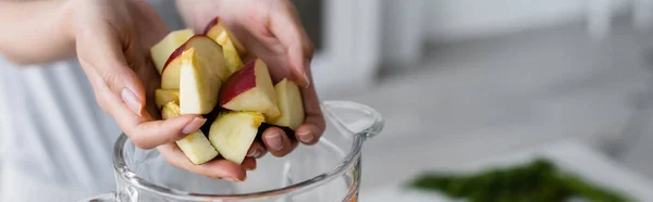 Vue recadrée des mains féminines avec pomme coupée près du pot de shaker, bannière — Photo de stock