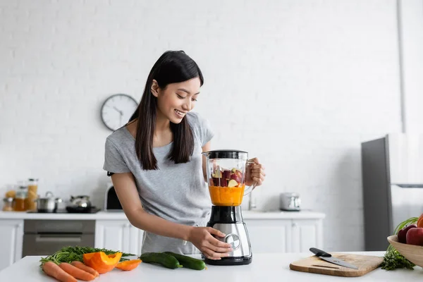 Happy asian woman preparing fresh smoothie for breakfast in kitchen — Stock Photo