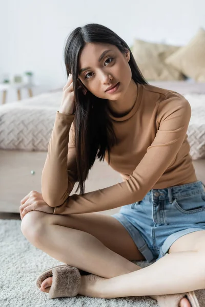 Asiatique femme assis sur sol et chambre à coucher et regarder caméra — Photo de stock