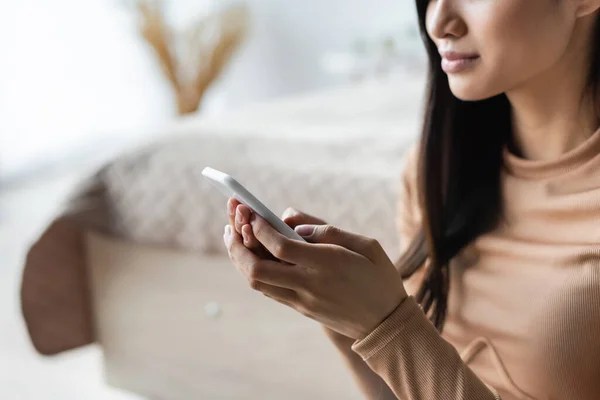 Teilbild einer jungen Frau, die zu Hause auf dem Handy tippt — Stockfoto