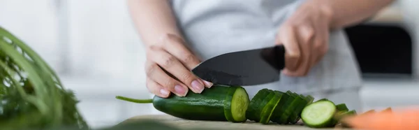 Vista recortada de la mujer borrosa cortando pepino fresco en la tabla de cortar, pancarta - foto de stock