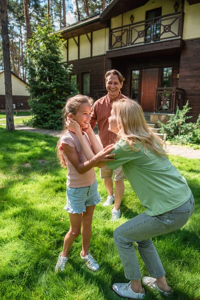 Smiling parent and daughter standing near father on lawn — Stock Photo
