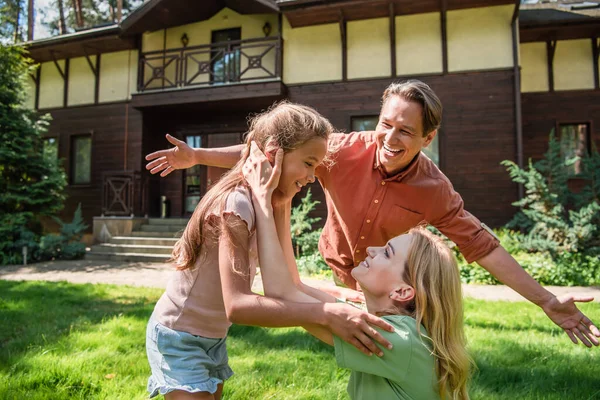 Positive mother touching kid near father on lawn — Stock Photo