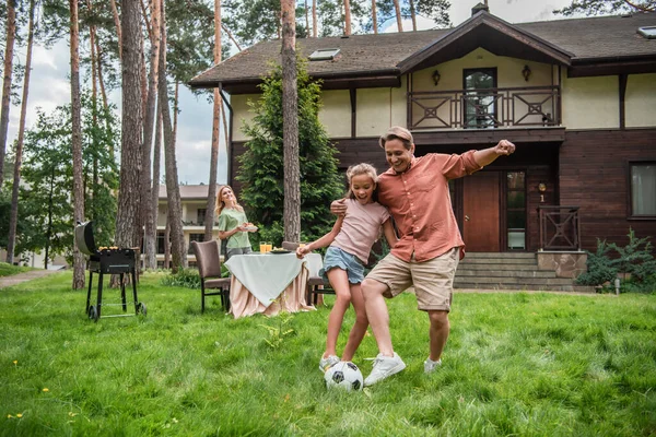 Smiling father hugging kid while playing football outdoors — Stock Photo