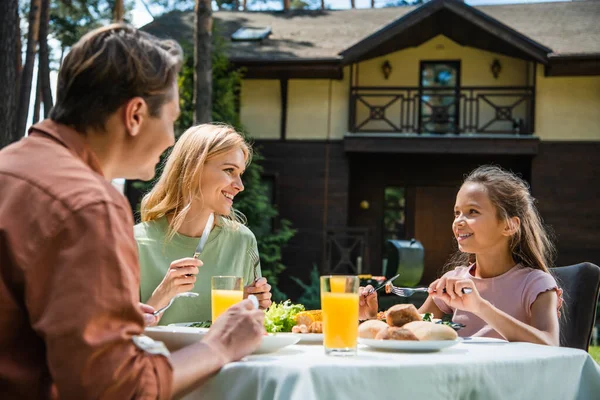 Famille souriante ayant pique-nique près de la maison de vacances floue — Photo de stock