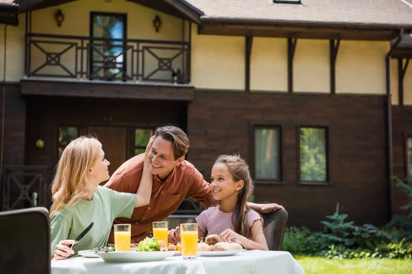 Smiling woman touching husband near daughter during picnic outdoors — Stock Photo