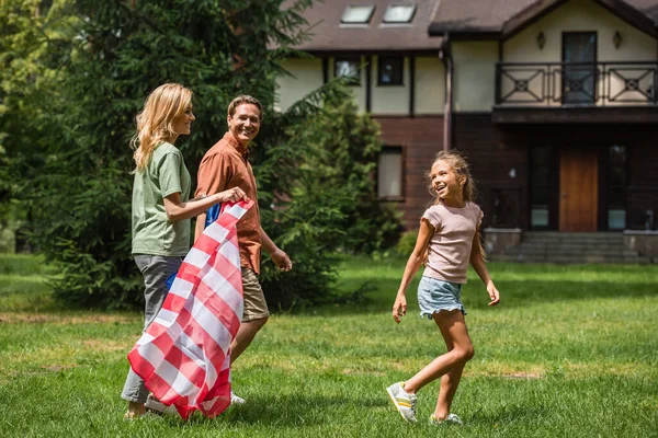 Donna sorridente con bandiera americana vicino a figlia e marito — Foto stock
