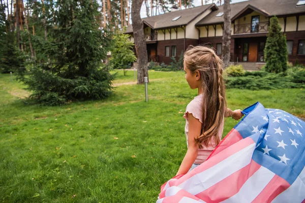 Девушка с американским флагом на газоне под открытым небом — стоковое фото