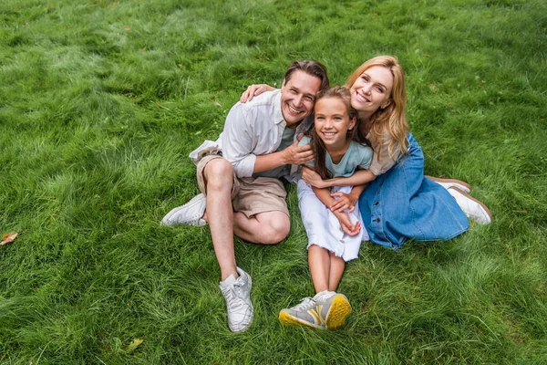 Blick aus der Vogelperspektive auf eine glückliche Familie, die sich im Gras umarmt — Stockfoto