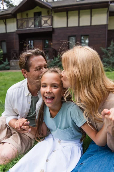 Parents holding hands and kissing excited kid outdoors — Stock Photo