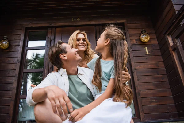 Low angle view of smiling family hugging on porch of vacation house — Stock Photo