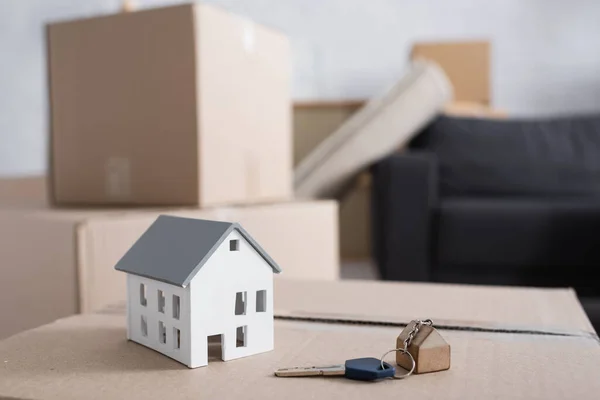 Clé et modèle de maison sur boîte en carton dans un nouvel appartement — Photo de stock