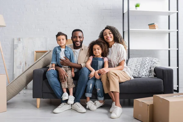 Afrikanisch-amerikanische Familie lächelt, während sie auf dem Sofa in neuer Wohnung sitzt — Stockfoto