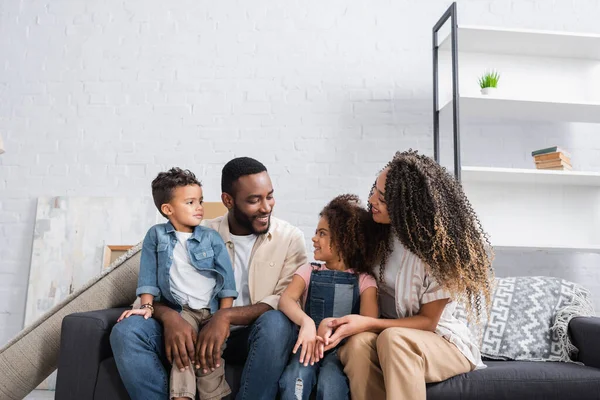 Happy african american family talking on couch in new apartment — Stock Photo