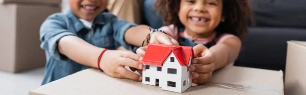 Abgeschnittene Ansicht von verschwommenen afrikanisch-amerikanischen Kindern in der Nähe des Hausmodells, Banner — Stockfoto