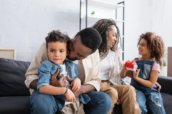 Heureuse famille afro-américaine assis sur le canapé dans un nouvel appartement — Photo de stock
