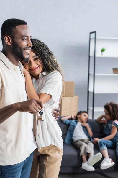 Homme afro-américain embrasser femme tout en tenant la clé de nouvel appartement — Photo de stock