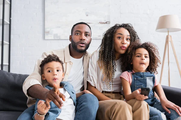 Familia afroamericana enfocada viendo películas en casa - foto de stock