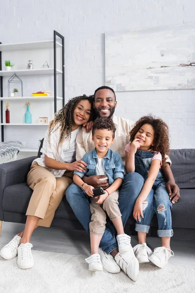 Cheerful african american couple watching tv with kids at home — Stock Photo