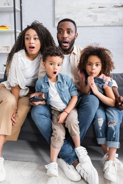 Família afro-americana espantada assistindo tv juntos em casa — Fotografia de Stock